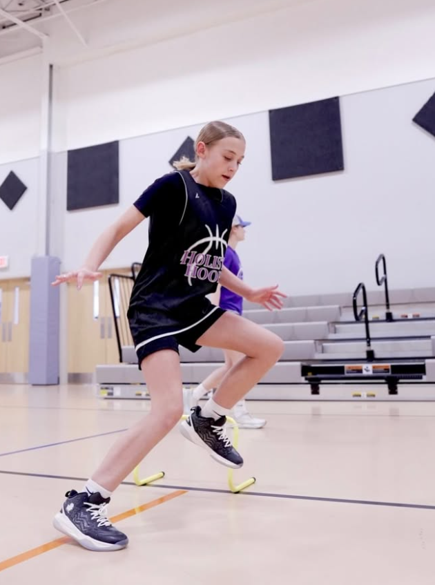 Athlete jumping over an agility hurdle during a footwork drill
